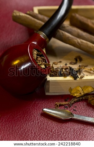 Pipe, tobacco, cigarettes, cigars, smoking, etc. on red leather background