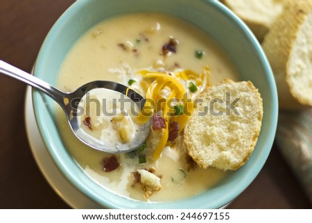 Creamy loaded baked potato soup with scallion garnished and fresh Italian bread