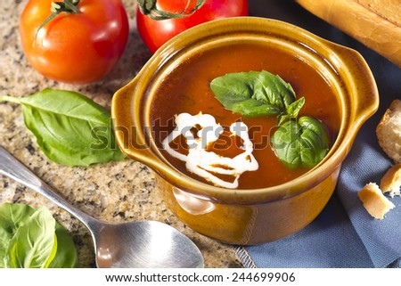 Homemade tomato and basil soup in the kitchen with fresh bread for dipping
