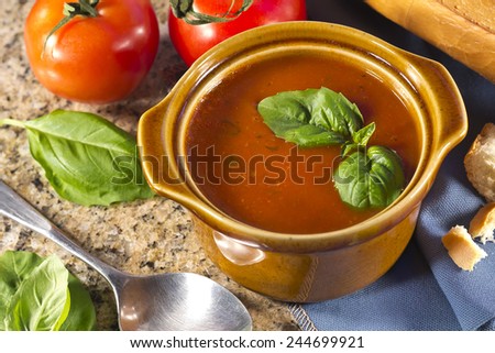 Homemade tomato and basil soup in the kitchen with fresh bread for dipping
