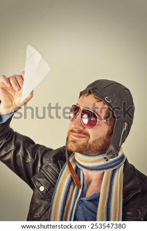 Aviator pilot with hat and sunglasses plays with paper planes