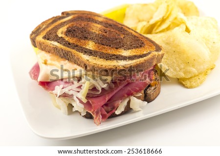 Famous New York Reuben corned beef sandwich with chips and a pickle