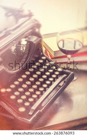 Old vintage typewriter with glass of wine pencils and books in this retro creative writing and relazation themed desk top