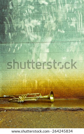 Old worn trumpet stands alone against a grungy wall outside a jazz club