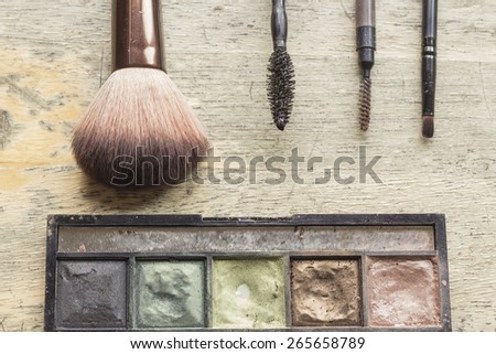 Used makeup kit on distressed wooden surface for beauty and cosmetics themed background