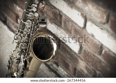 Lone old saxophone leans against brick wall outside abandoned jazz club