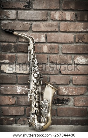 Lone old saxophone leans against brick wall outside abandoned jazz club