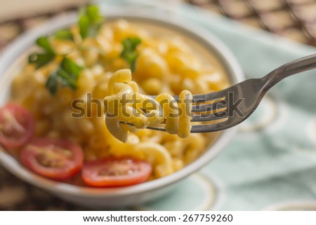 Delicious macaroni and cheddar cheese with fresh sliced grape tomatoes and parsley sprig