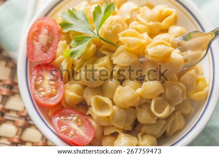 Delicious macaroni and cheddar cheese with fresh sliced grape tomatoes and parsley sprig