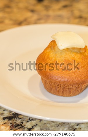 Single fresh corn muffin with slice of butter