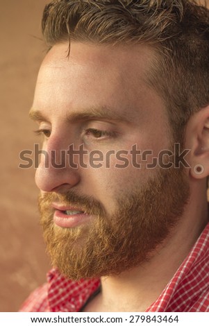 Portrait of bearded young man with gauged ears and stylish hair