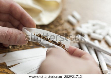 Rolling cigarettes with filters papers and plenty finely cut tobacco