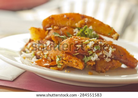 Spicy fried Indian potato wedges with coriander and coconut shavings