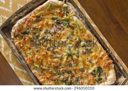 Home made artisan veggie pizza pie with onions peppers spinach and olives
