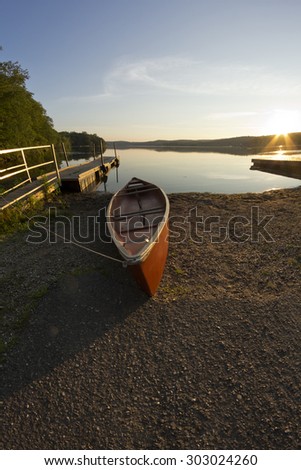 Red canoe on lake shore at dusk in fisheye nature shot