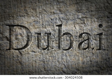 Engraving spelling the city Dubai on textured old surface