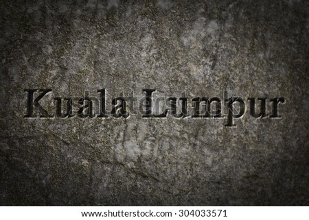 Engraving spelling the city Kuala Lumpur on textured old surface