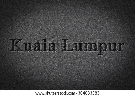Engraving spelling the city Kuala Lumpur on textured old surface