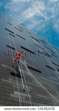 Cleaning service - A man cleaning windows on a high rise building