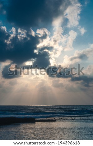 Black clouds on the blue sky and sun rays