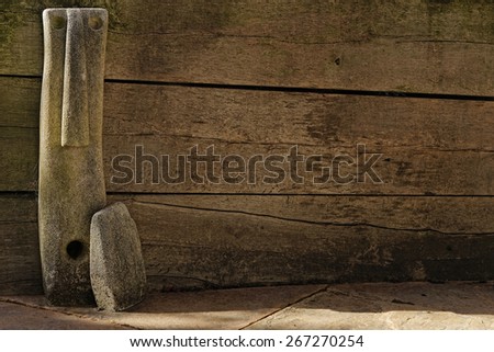 Concrete statue of stylized elongated face and hand against weathered wooden fence [landscape format].