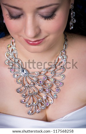 Woman Looks Down with Large Necklace. Shallow Depth of Field with Focus on Large jewel.