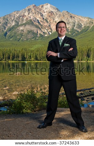 Man in Tuxedo Stands Confidently Near Mountain