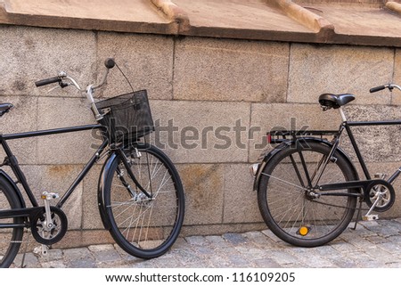 Two old classic bicycles near the stone wall