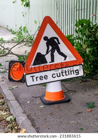 Tree cutting safety sign and cone on the street warning about of danger zone with fallen branches and sawdust on the asphalt
