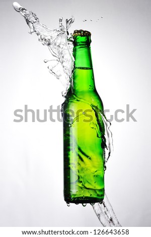 Green beer bottle and a water splash