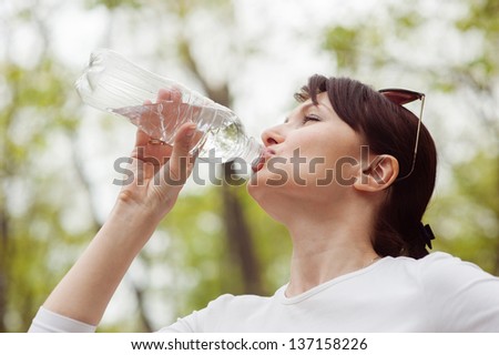 Woman drinks water from a bottle on a nature
