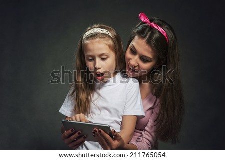 Two happy girls hold and play with tablet pc