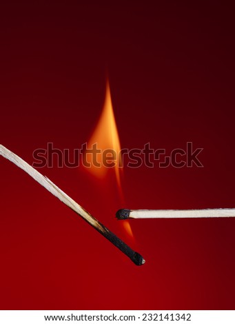 Macro shot of a flaming matchstick on a red background