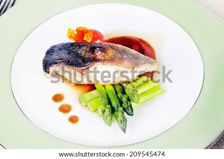 white fish with asparagus and white wine in a restaurant