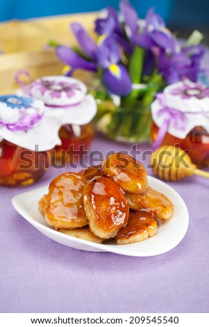 cheese pancakes with honey in a still life with jars, spoon for honey and flowers