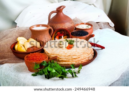 stack of pancakes with red and black caviar in a still life with pottery and jug with milk