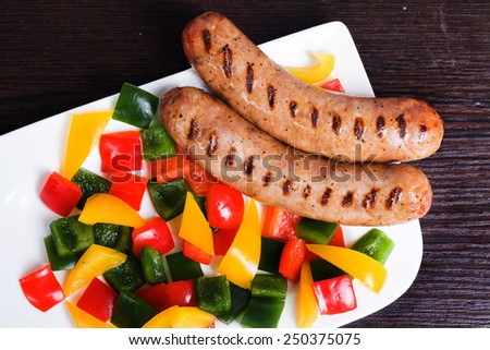 Grilled sausages with easy side dish of peppers, yellow, green, red curls on top