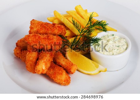 Breaded fish sticks with french fries, lemon, dill and sauce on a plate for menus closeup on a white background