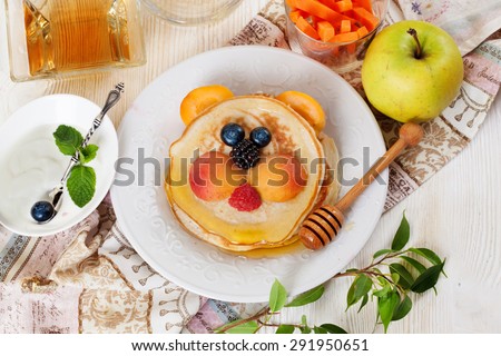 Children\'s breakfast lunch pancakes smiling face of the sun lion strawberry blueberry and apricot, cute food, honey, creative idea dinner