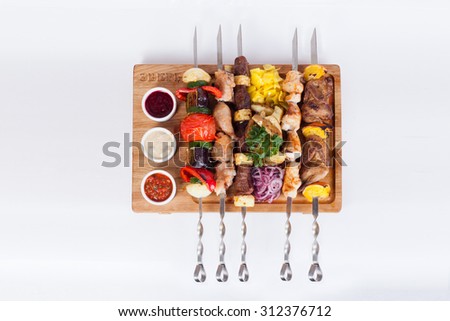 assorted skewers of meat and vegetables, quail skewers on a board with mayonnaise sauce ketchup garchitsa on a white background isolation