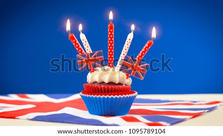 Red white and blue theme cupcakes and cake stand with UK Union Jack flags for Queen\'s Birthday weekend celebration or Great Britain party food.