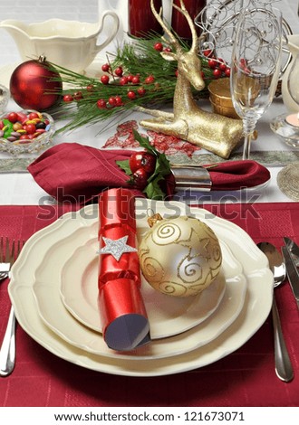 Modern and stylish Christmas dinner table setting including plates, glasses and place mats and Christmas decorations. Red and white table decorated for Christmas Day. (Vertical)