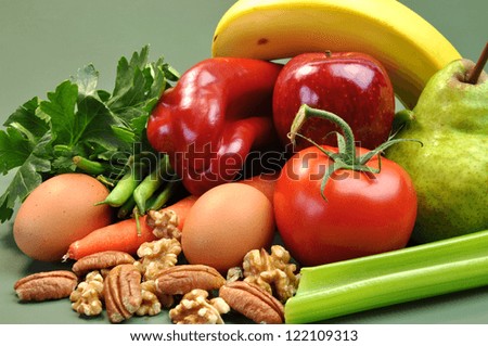 Group of wholesome, organic food, including pear, apple, tomato, eggs, nuts, pecans, walnuts, carrot, banana, and apple, for a healthy diet or slimming New Year resolution.