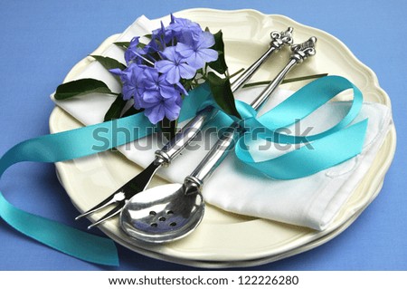 Blue theme table setting with beautiful silver cutlery, plates and serviette napkin for a modern twist on traditional table elegance.