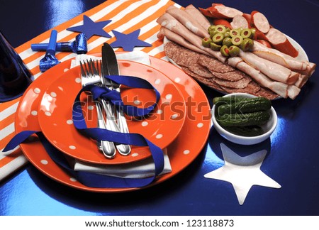 Football party table settings celebration in navy blue, orange and white team colors, with party food.