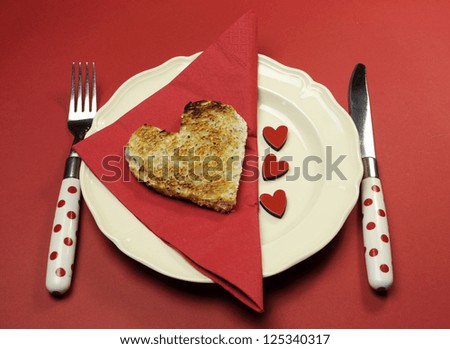 Red theme breakfast table setting with heart shape toast with love hearts on red background for Valentine, Christmas, Birthday, Mothers Day or special occasion.