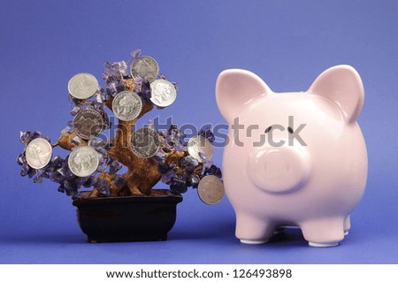 Money Tree and Savings concept with coins hanging from a crystal tree with Piggy Bank against a blue background.
