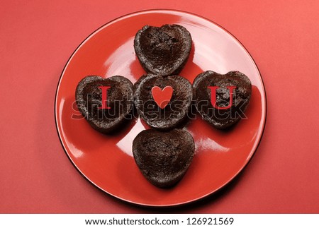 Romantic love theme mini chocolate cupcake muffins with letters spelling, I Love (heart) You, on red red plate and background for Valentine, Christmas, Easter, birthday, or Mothers Day.