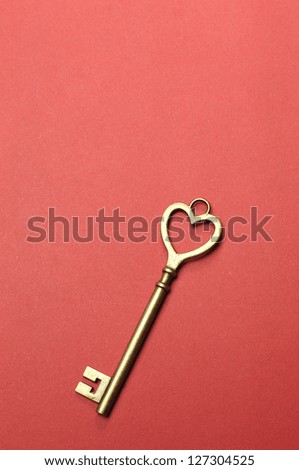Heart shape key for \'key to my heart\', \'key to my success\' or business \'key performance indicator\' concept, on red background. Vertical with copy space for your text here.