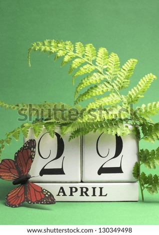 Earth Day, save the date white block calendar, April 22, with butterfly and ferns against a green background. Vertical with copy space.